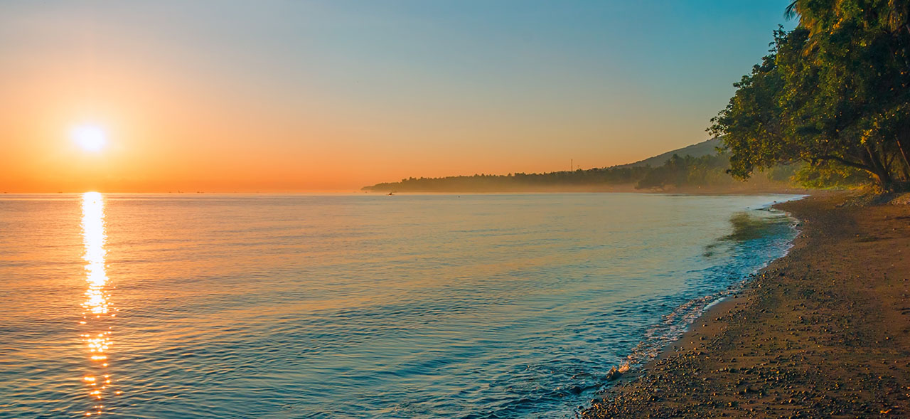 Image of a beach with sunset over the horizon in Bali, Indonesia.