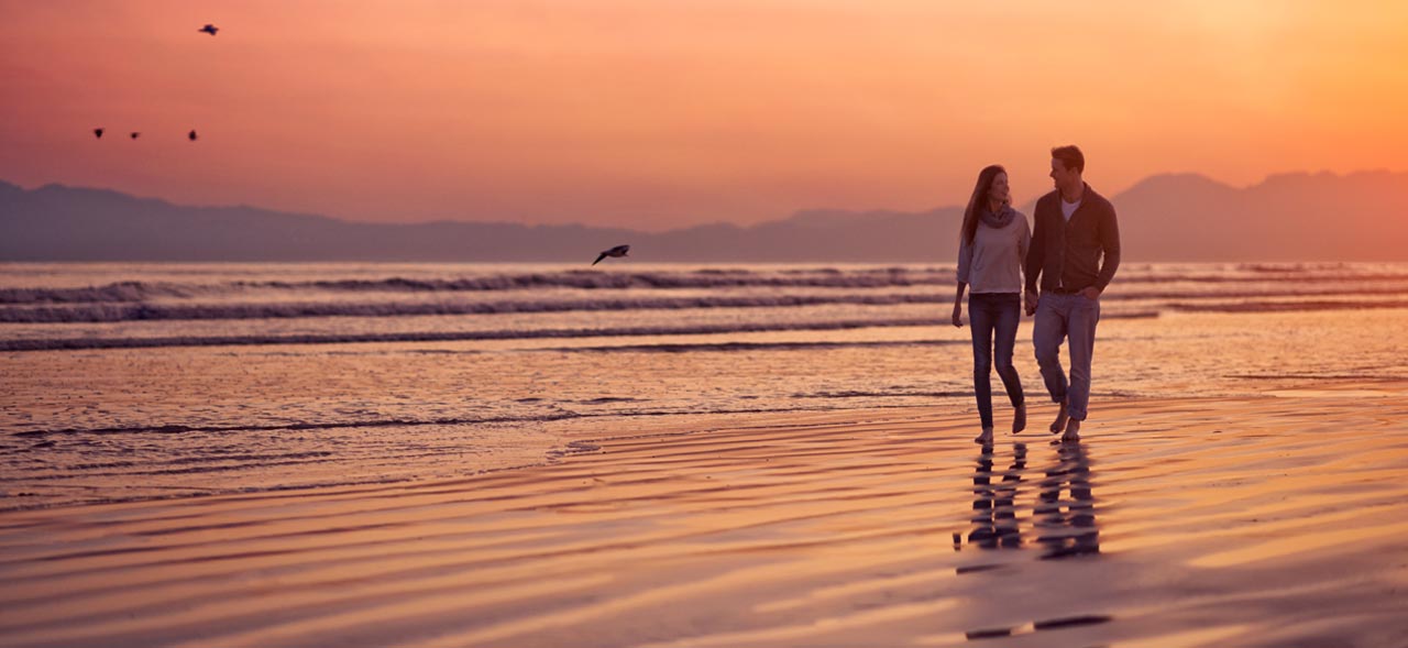 Silhouette of a young couple enjoying a romantic walk on the beach.