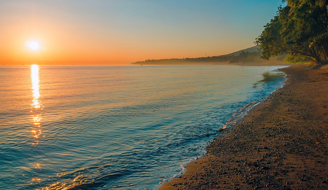 Image of a beach with sunset over the horizon in Bali, Indonesia.