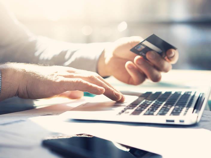 Image of a man holding a credit card and using a laptop